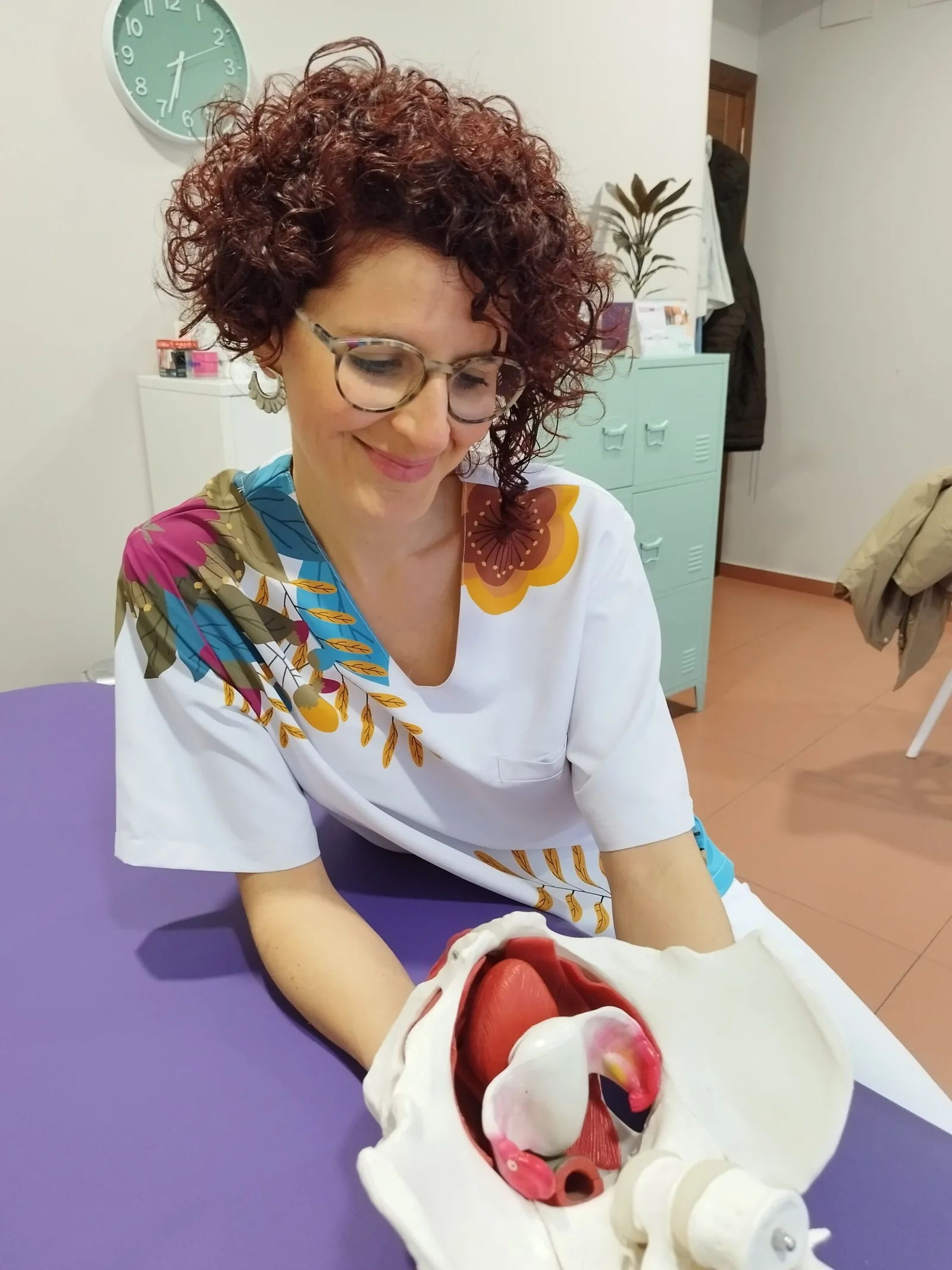 Profesional sanitaria realiza una demostración con el modelo anatómico de pelvis.