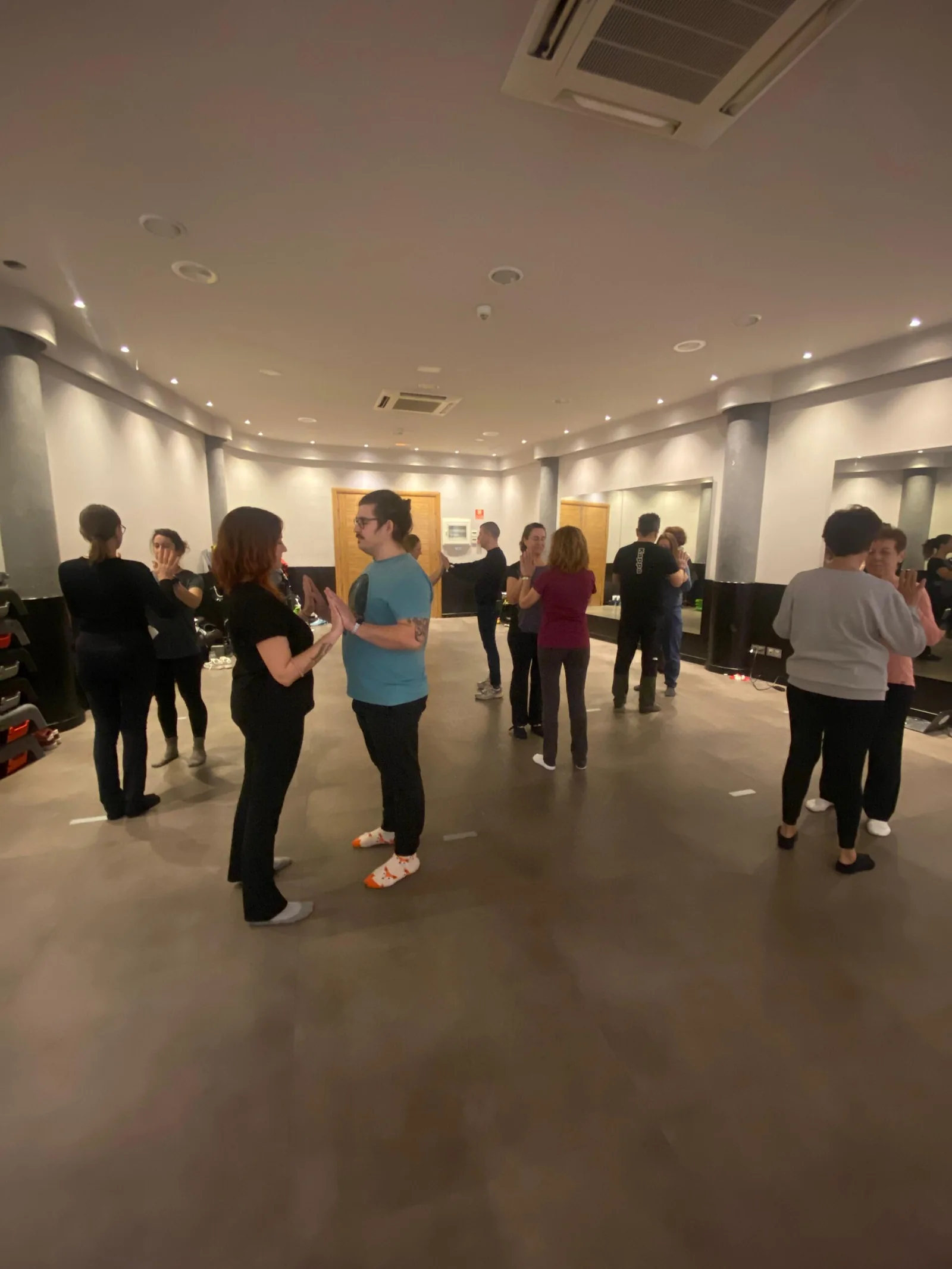 Participantes de pie en una sala amplia, hablando por parejas durante un taller