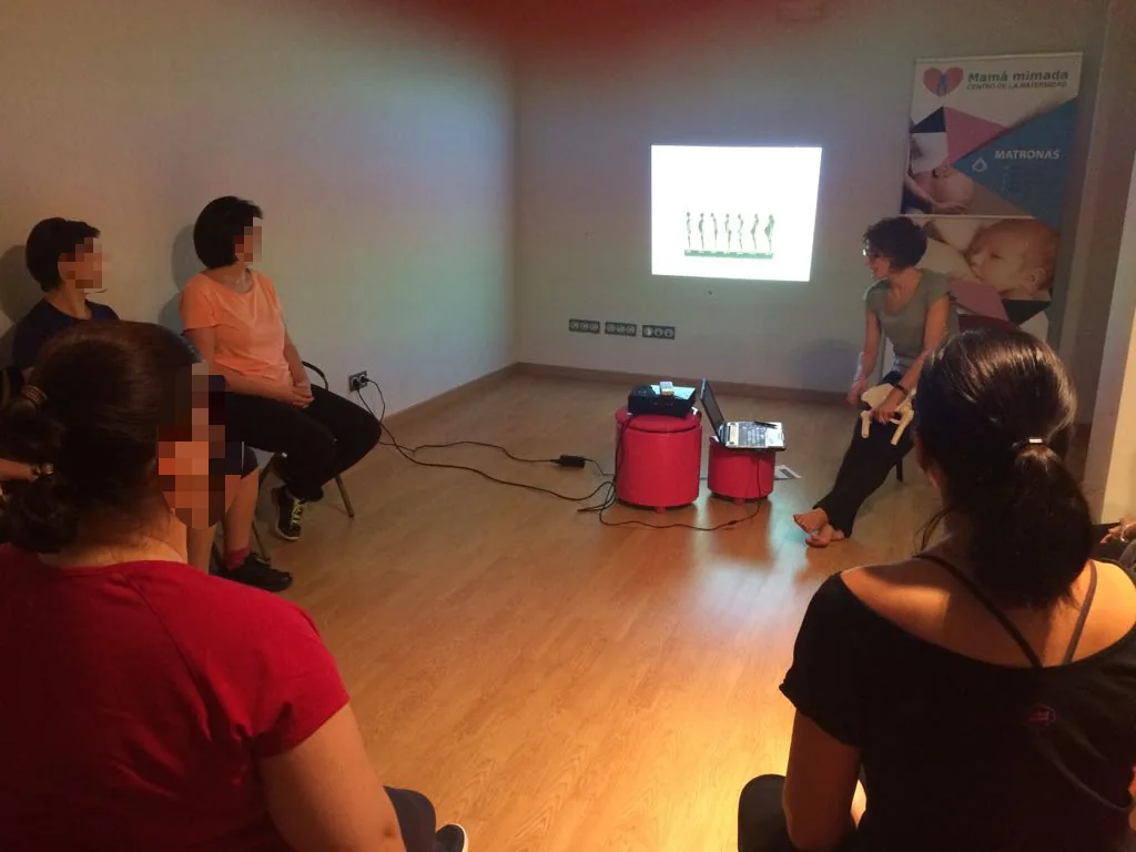 Grupo sentado en una sala escuchando una charla con una proyección en la pared